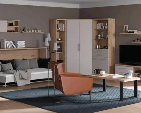 Wohnbereich mit weissem Sofa vor langer Holzrückwand und Wandregalen, davor Holztisch mit schwarzem Gestell, oranger Sessel auf dunklem Teppich, rechts Schrankwand und TV-Board.
